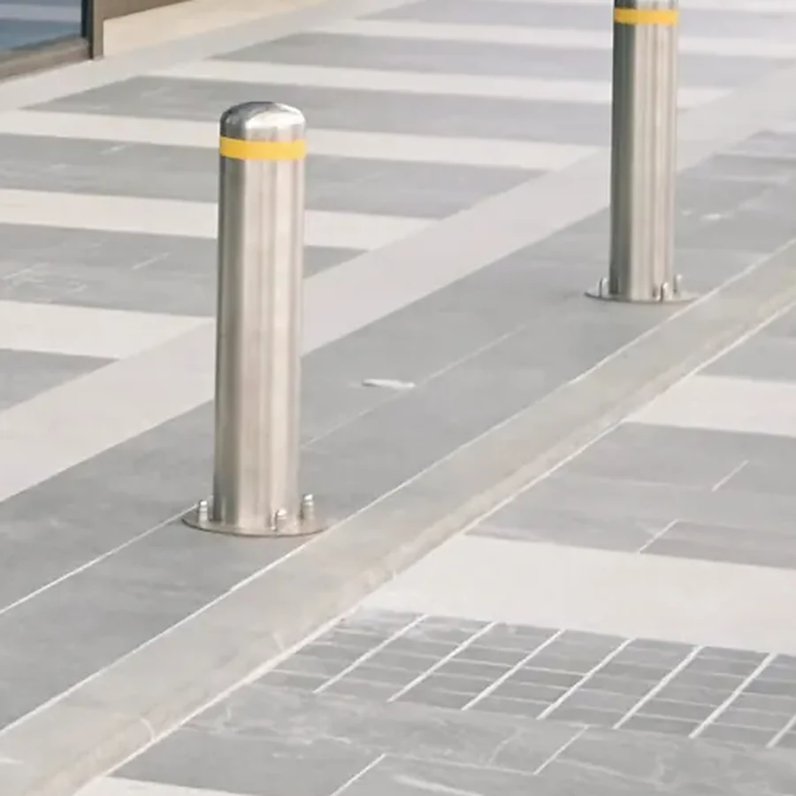 Stainless safety bollards with yellow bands on a paved commercial frontage