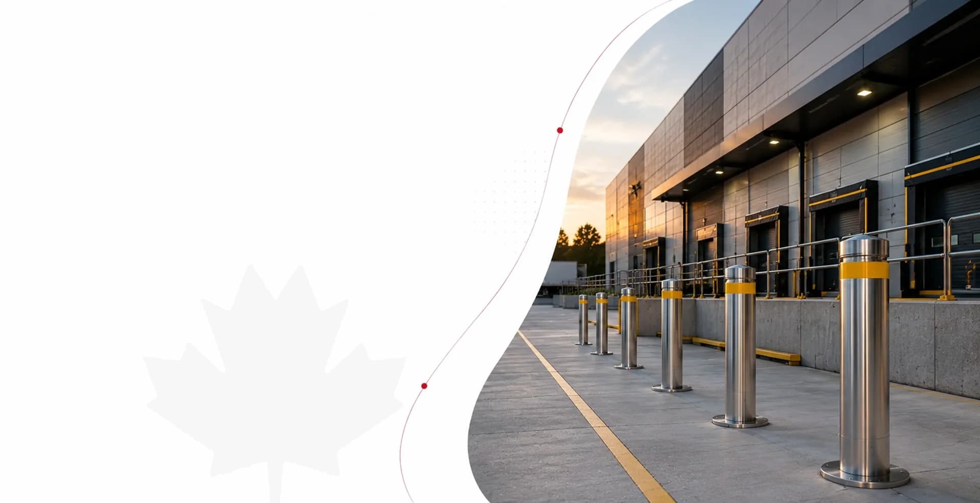 Stainless bollards with yellow bands guarding a row of loading dock doors at sunset