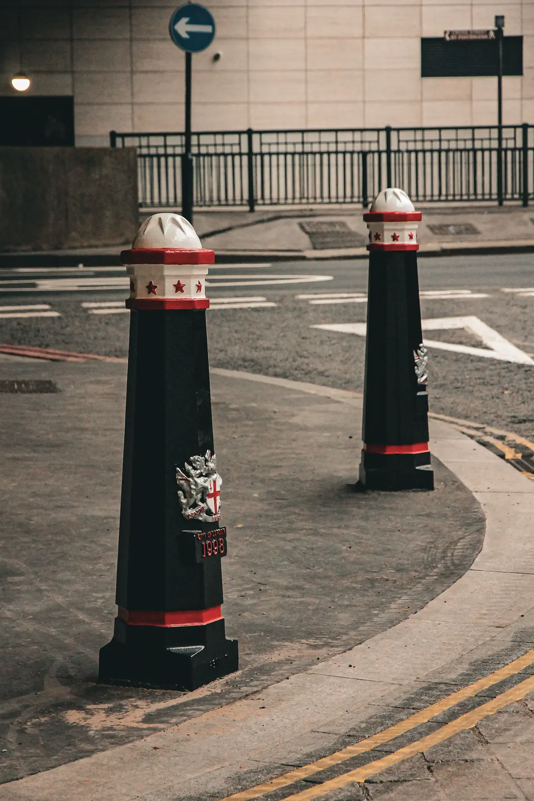 Two black bollards with red and white banding marking a city street corner